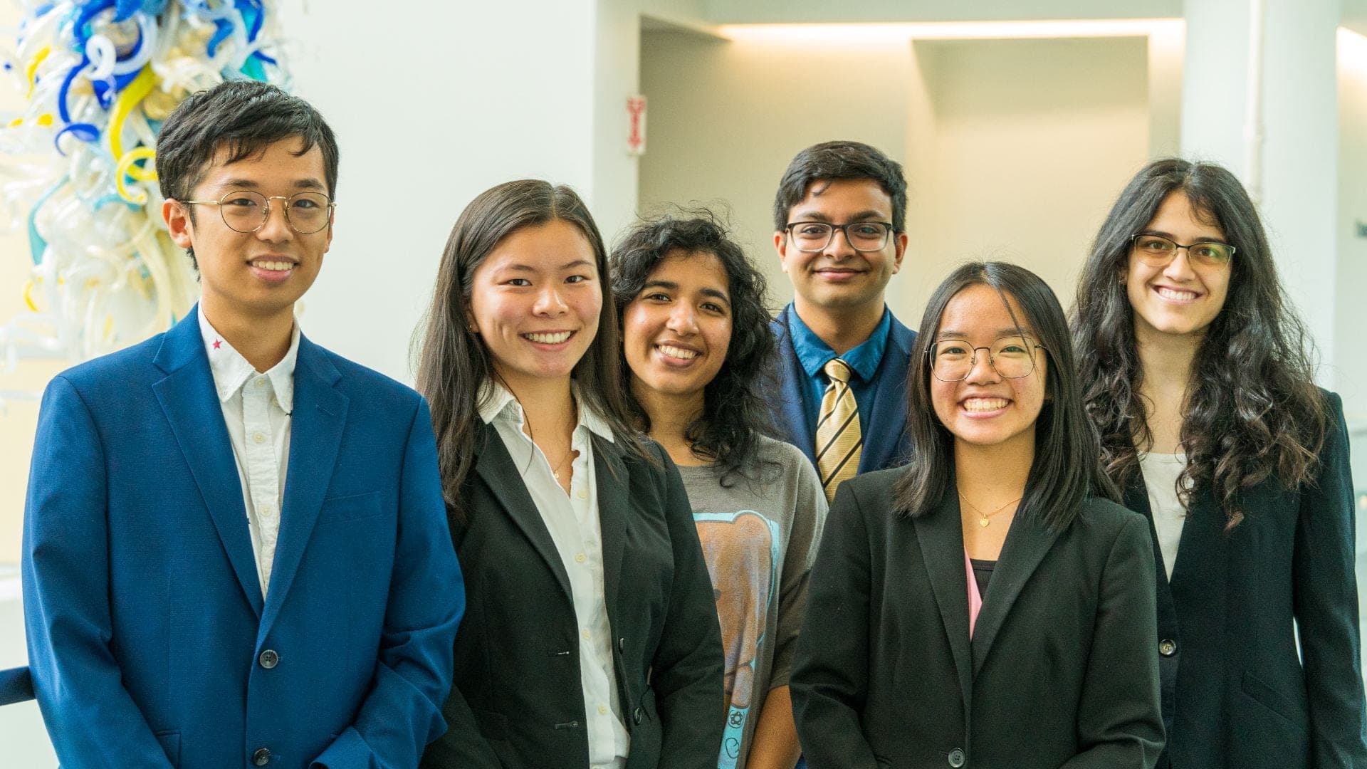 Six SASE GT officers in business attire standing together indoors.