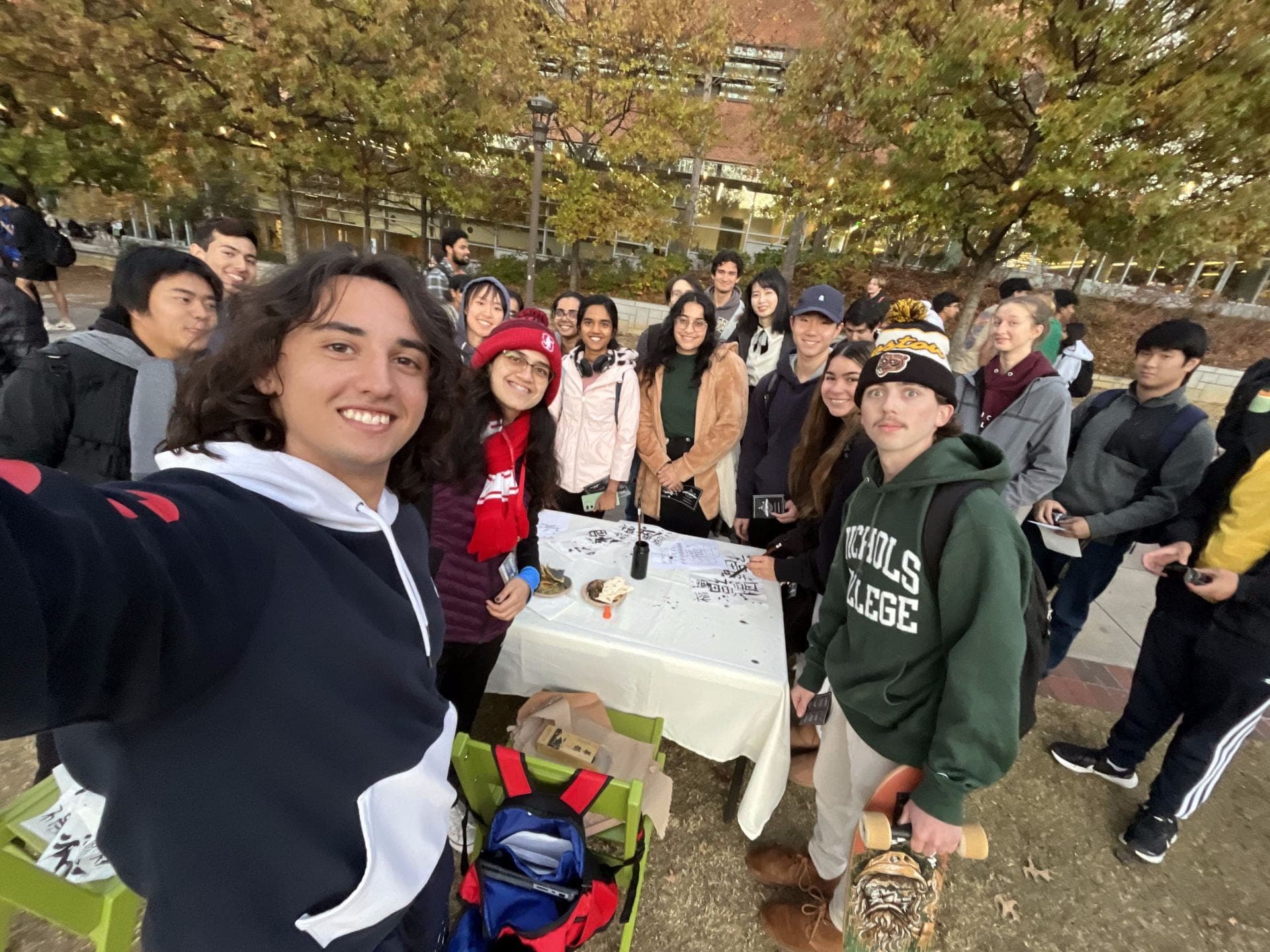 SASE GT members gathered around an outdoor table on campus at a calligraphy activity in autumn.