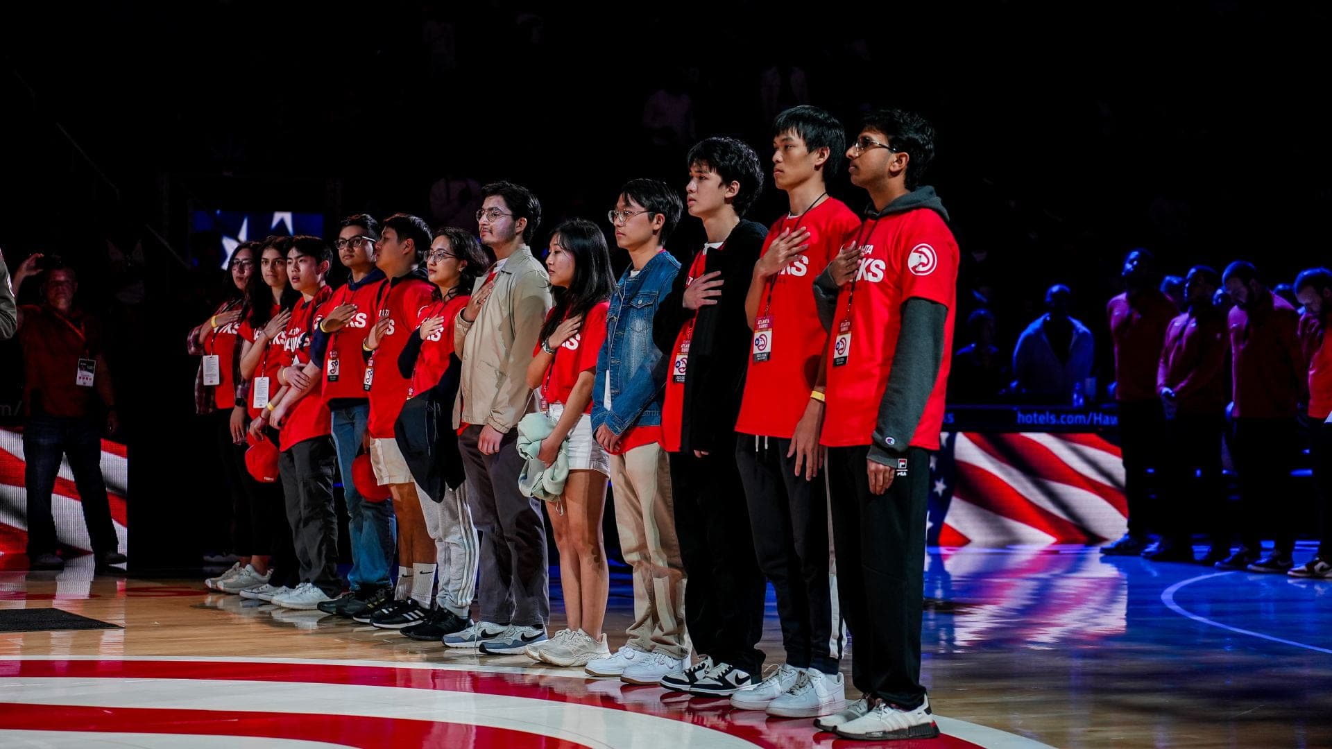 SASE GT members standing on the court in red shirts during an Atlanta Hawks game.